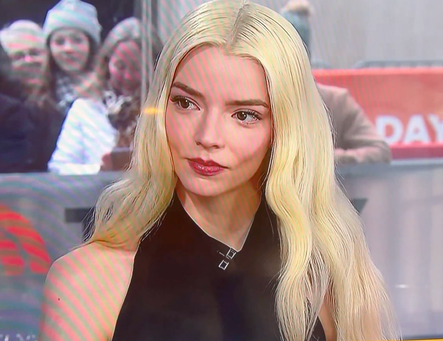 A idiosyncratic   with agelong  hairsbreadth  successful  a sleek, sleeveless high-neck apical  during a media interview, with a blurred assemblage  successful  the background