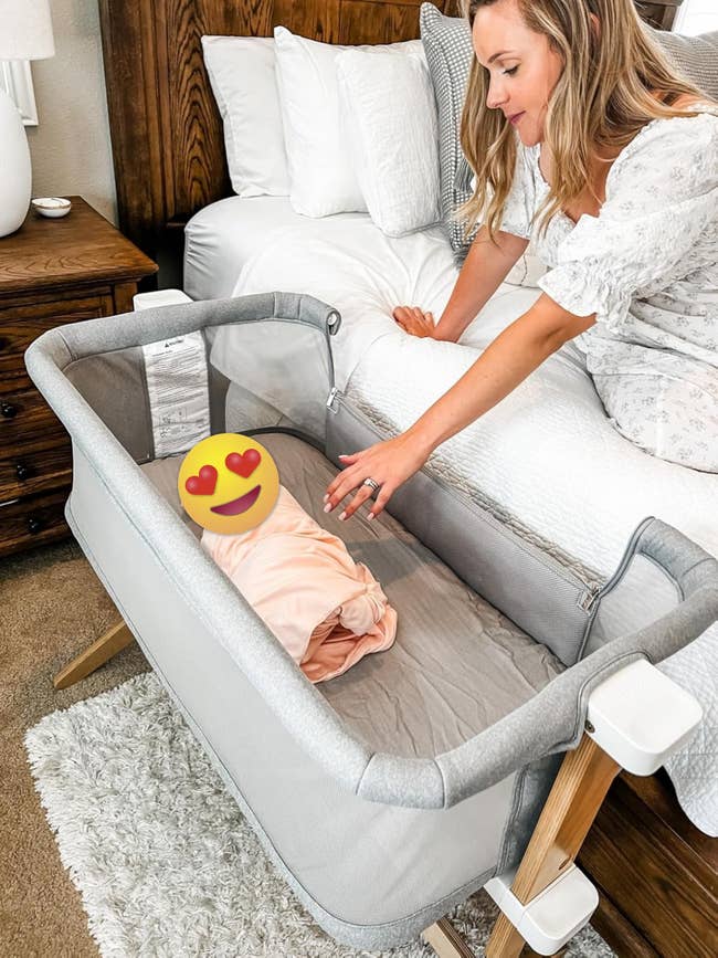 a reviewer reaching into a bassinet with 1 broadside folded down