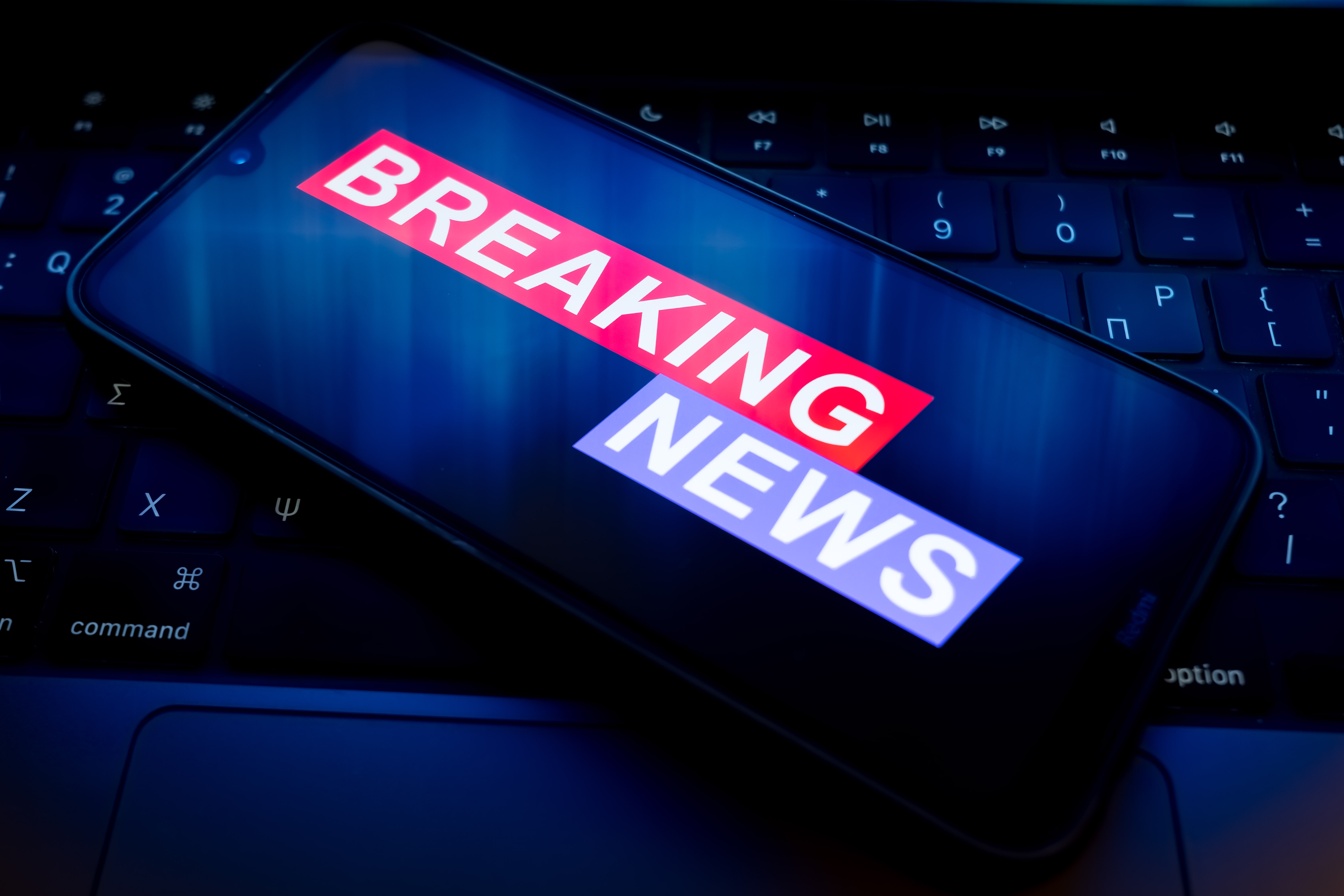 Smartphone connected  a keyboard displaying the substance   "Breaking News" connected  its screen