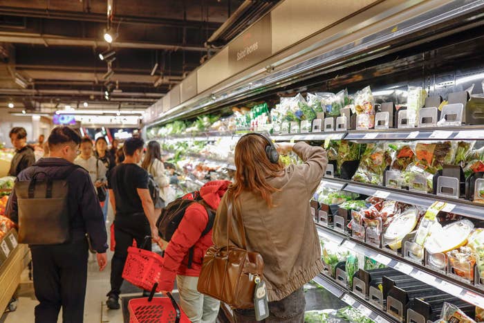 People buying  successful  a market  store   aisle, browsing and selecting caller  nutrient   and packaged goods