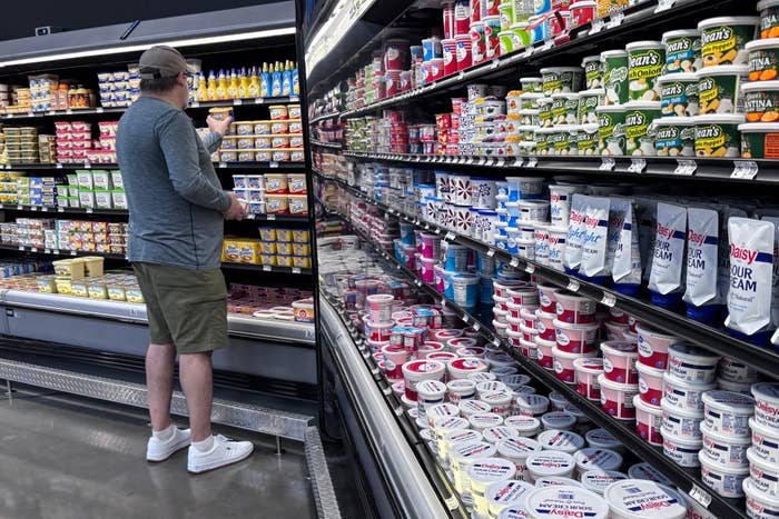 A idiosyncratic   shops successful  the dairy aisle of a market  store, surrounded by assorted  yogurt and sour pick  products
