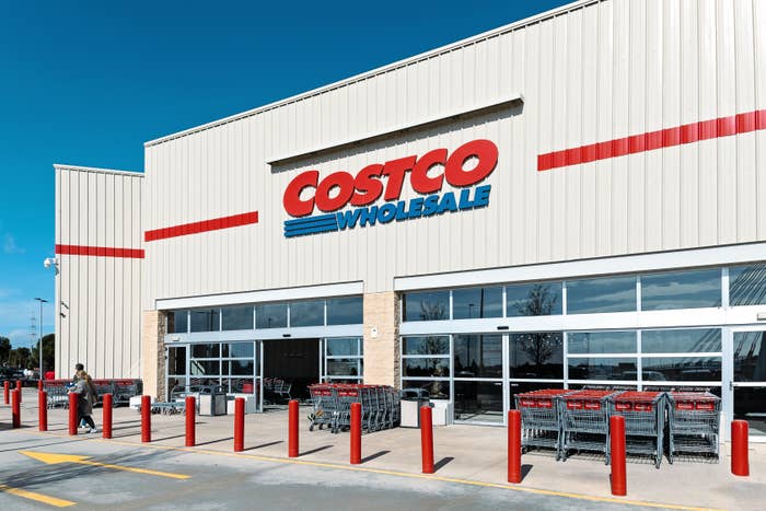 Exterior of a Costco Wholesale store with shopping carts outside and a person near the entrance