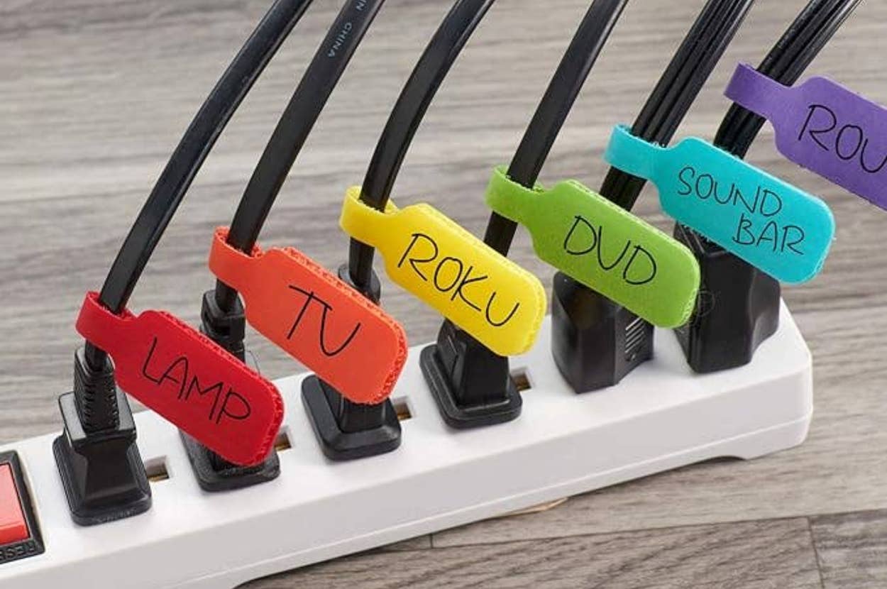 Power strip with labeled cords for lamp, TV, Roku, DVD, sound bar, and router, each with a colorful tag for easy identification. Perfect for home organization