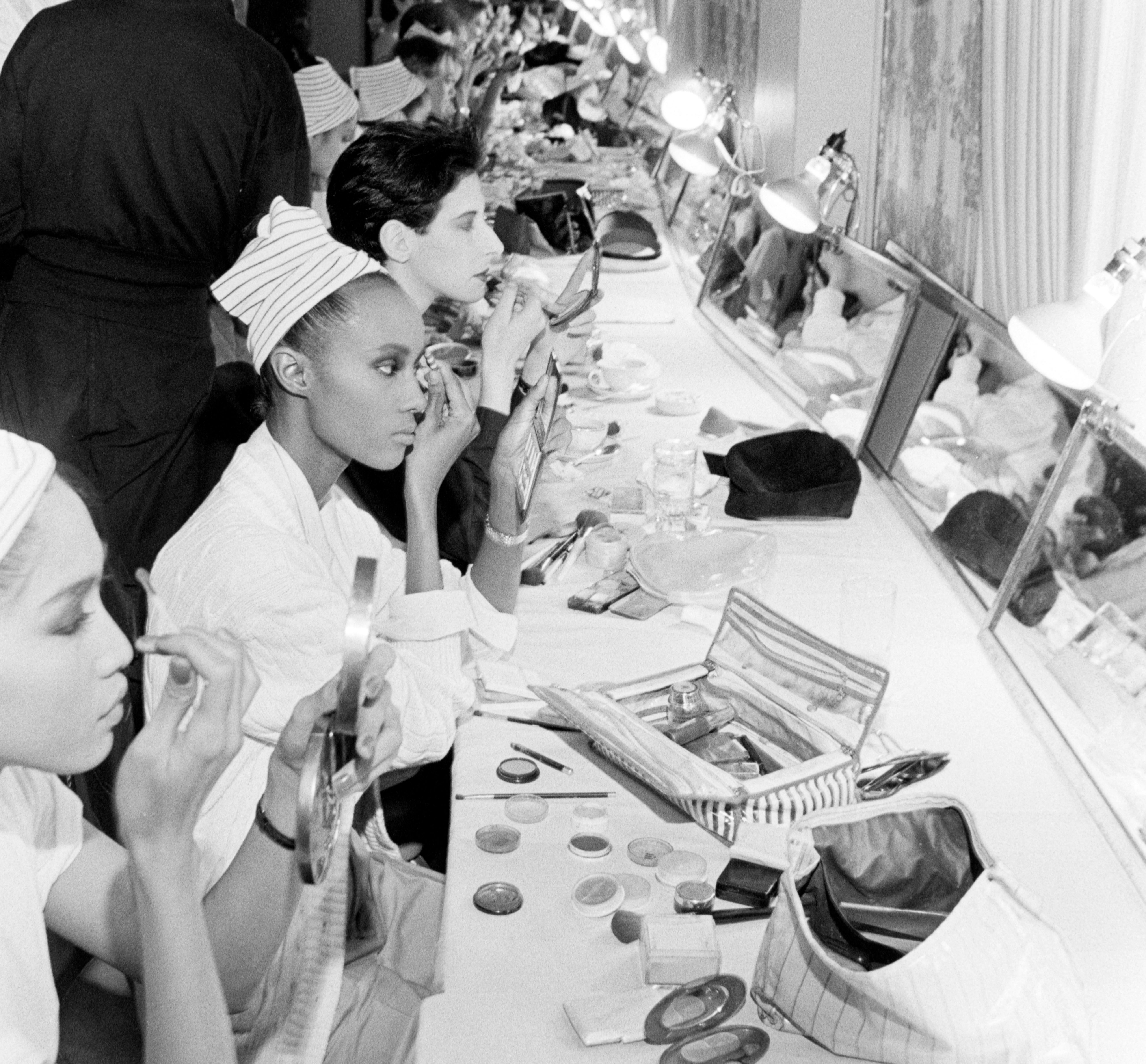 Models successful a backstage dressing country use makeup, wearing striped headbands. A engaged and glamorous pre-show mentation scene