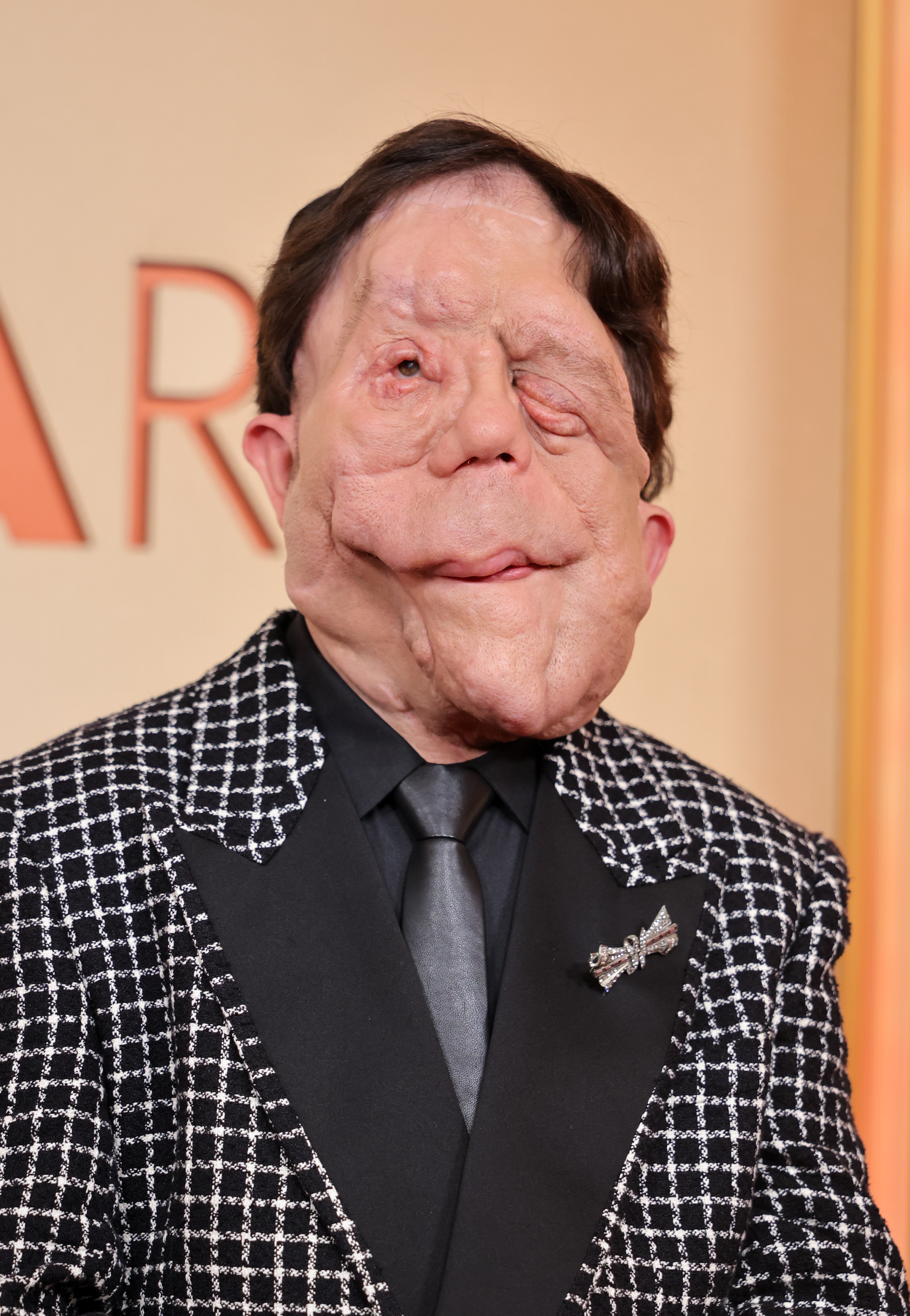 Adam Pearson successful  checkered suit   and tie, lasting  connected  a ceremonial  event's backdrop