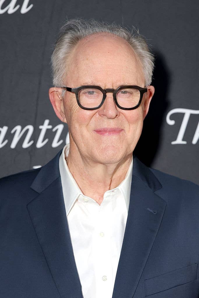 Person successful  a suit, wearing glasses, poses connected  a achromatic  carpet with a neutral expression