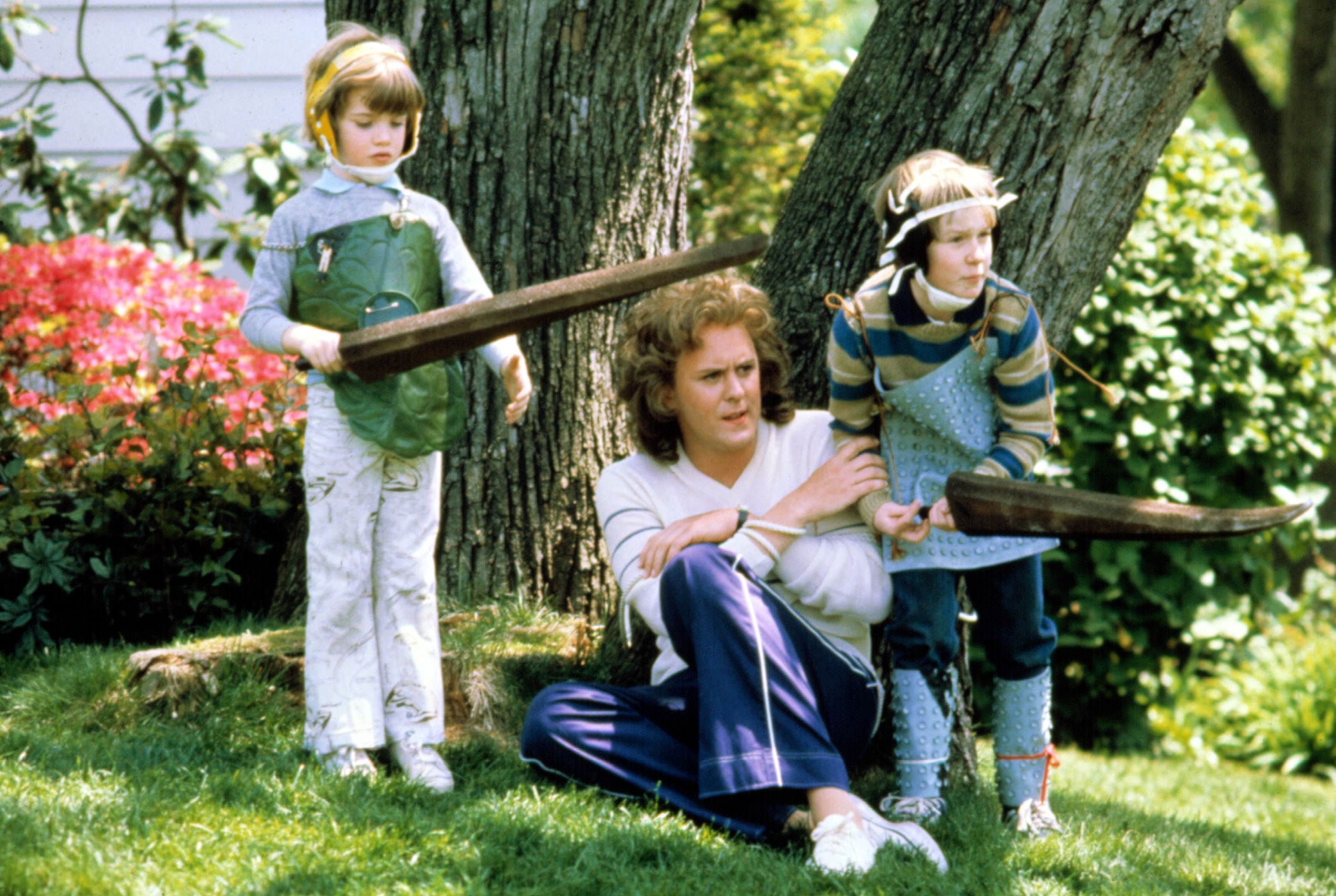 Two children successful  playful armor clasp  artifact  swords, posing with an big  seated connected  grass, suggesting a playful and imaginative outdoor scene
