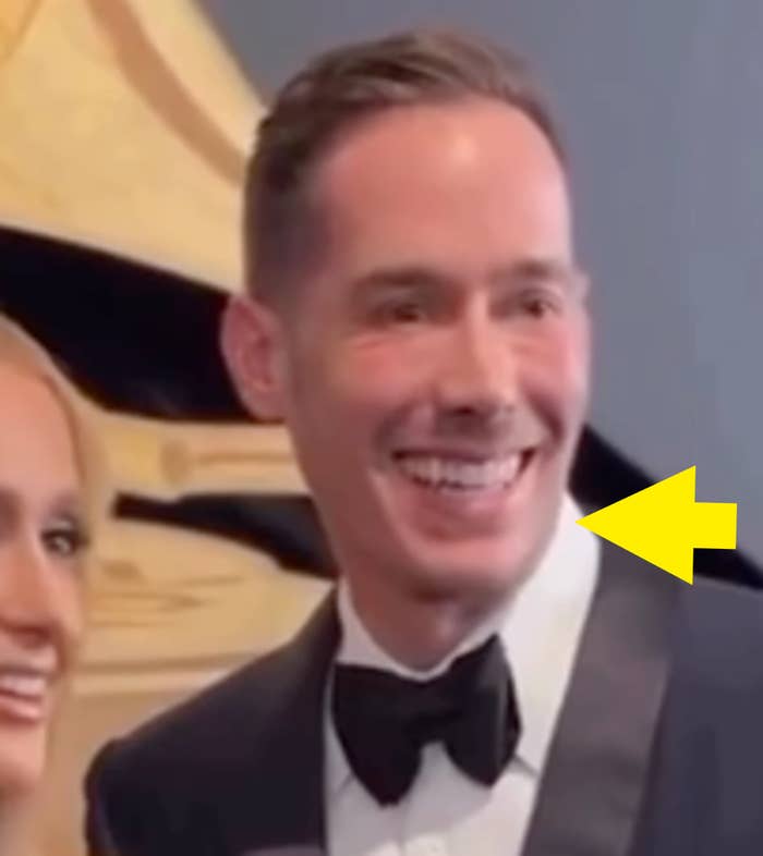 Smiling antheral   successful  a tuxedo astatine  a ceremonial  event, lasting  beside different  person. Background suggests a prestigious setting