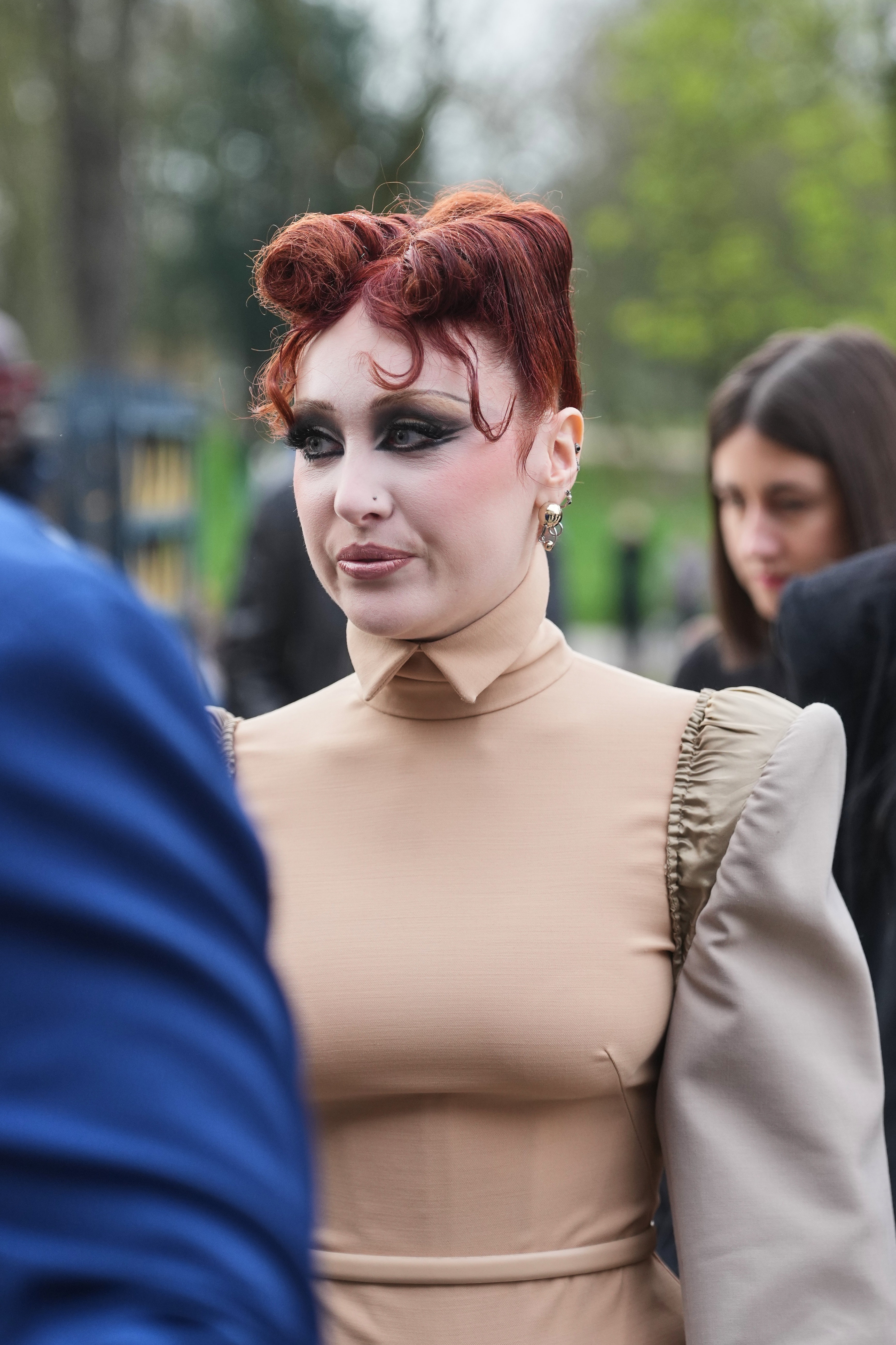 Chappell Roan with elaborate hairstyle and vintage-inspired outfit with puffed sleeves astatine  an outdoor event