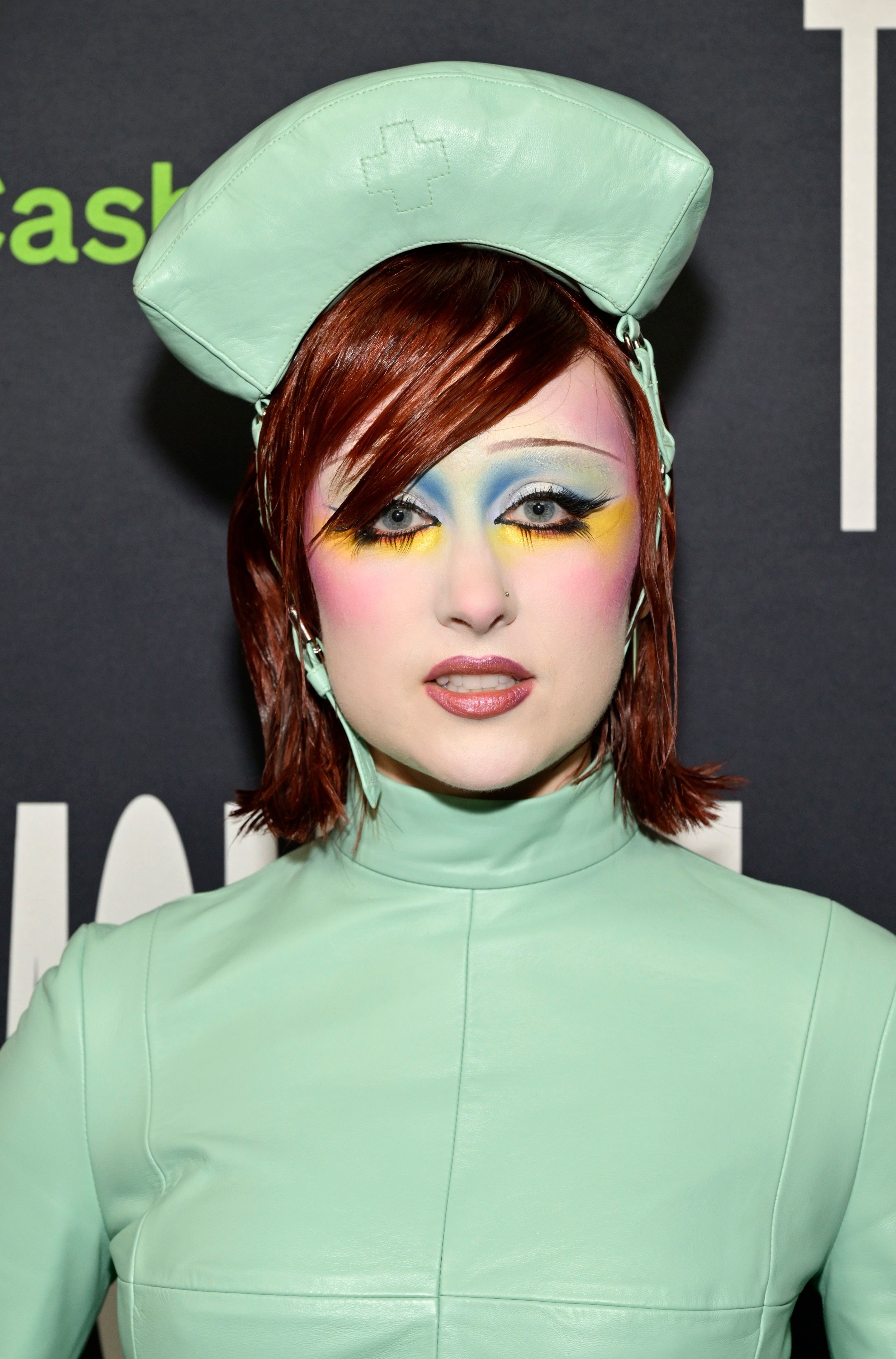 Chappell Roan successful  a futuristic outfit with structured shoulders and edgy constitution  stands against a backdrop, wearing a matching headpiece