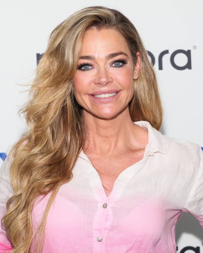 Denise Richards smiling astatine  an event, wearing a casual button-down garment  with relaxed hairsbreadth  style