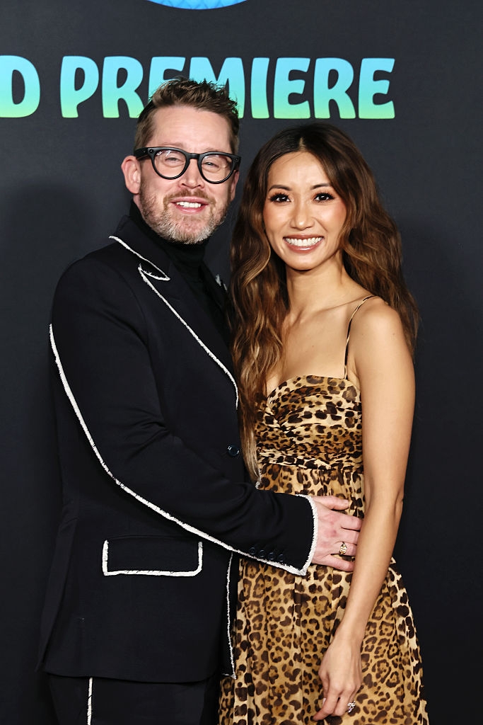 Two radical posing connected a reddish carpet. One is wearing a achromatic suit with achromatic trim, and the different is successful a leopard people dress