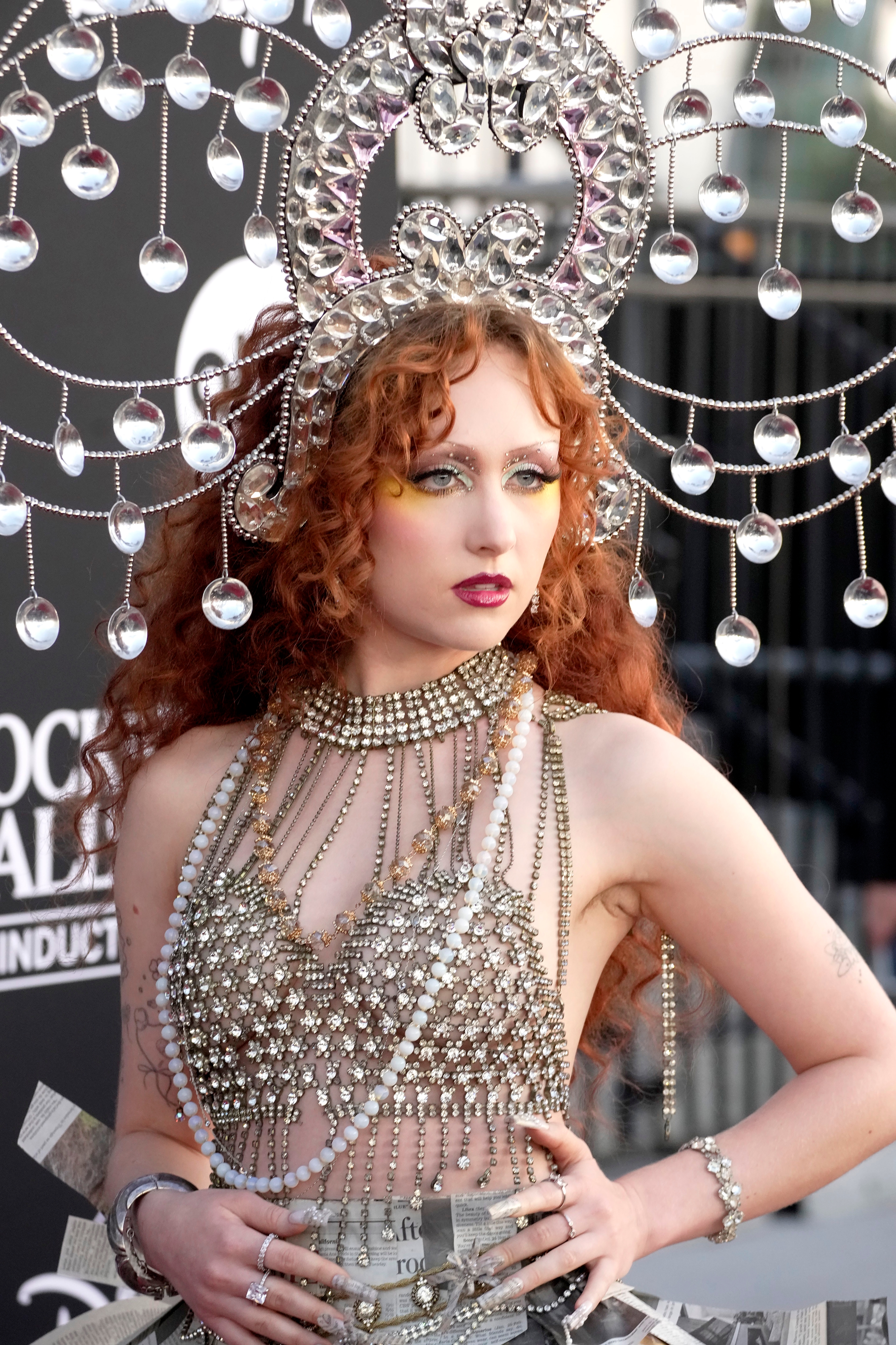 Person successful an ornate outfit with intricate jewelry headpiece and mesh-like top, posing confidently connected a reddish carpet