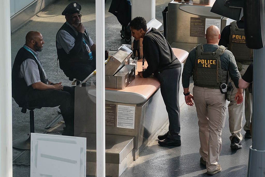 Two information officers astatine a booth interact with a idiosyncratic portion 2 ICE agents basal nearby