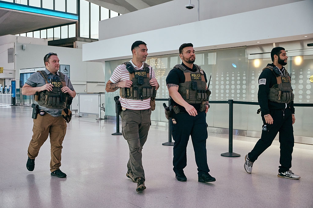 Four constabulary officers successful tactical vests locomotion done an airdrome terminal, appearing alert and focused