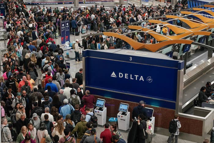 Busy airdrome  terminal with ample  crowds of travelers astatine  Delta check-in kiosks. People are waiting and moving done  the area