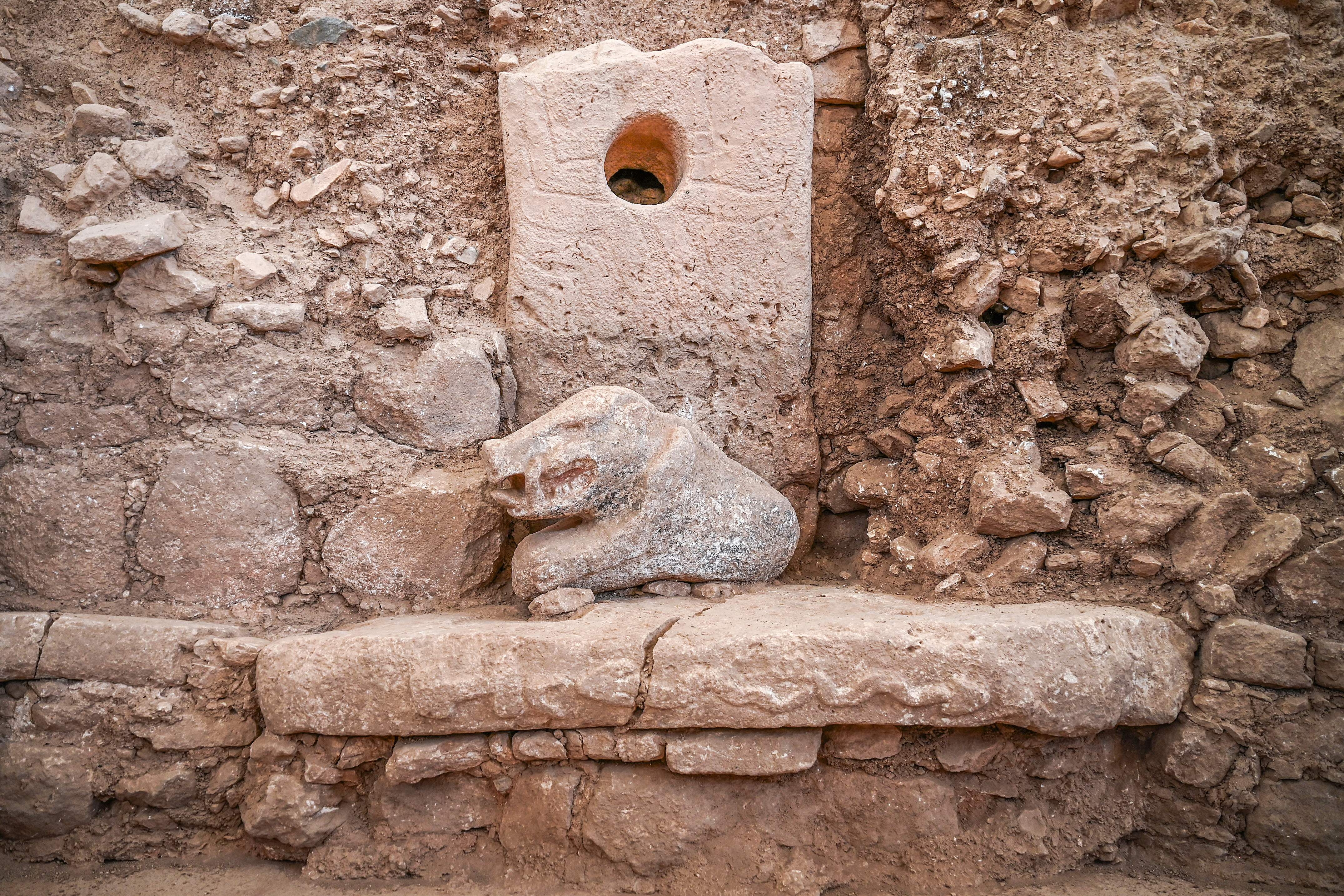 Ancient chromatic ruins featuring a carved carnal fig astatine an archaeological site, surrounded by weathered rocks and stonework