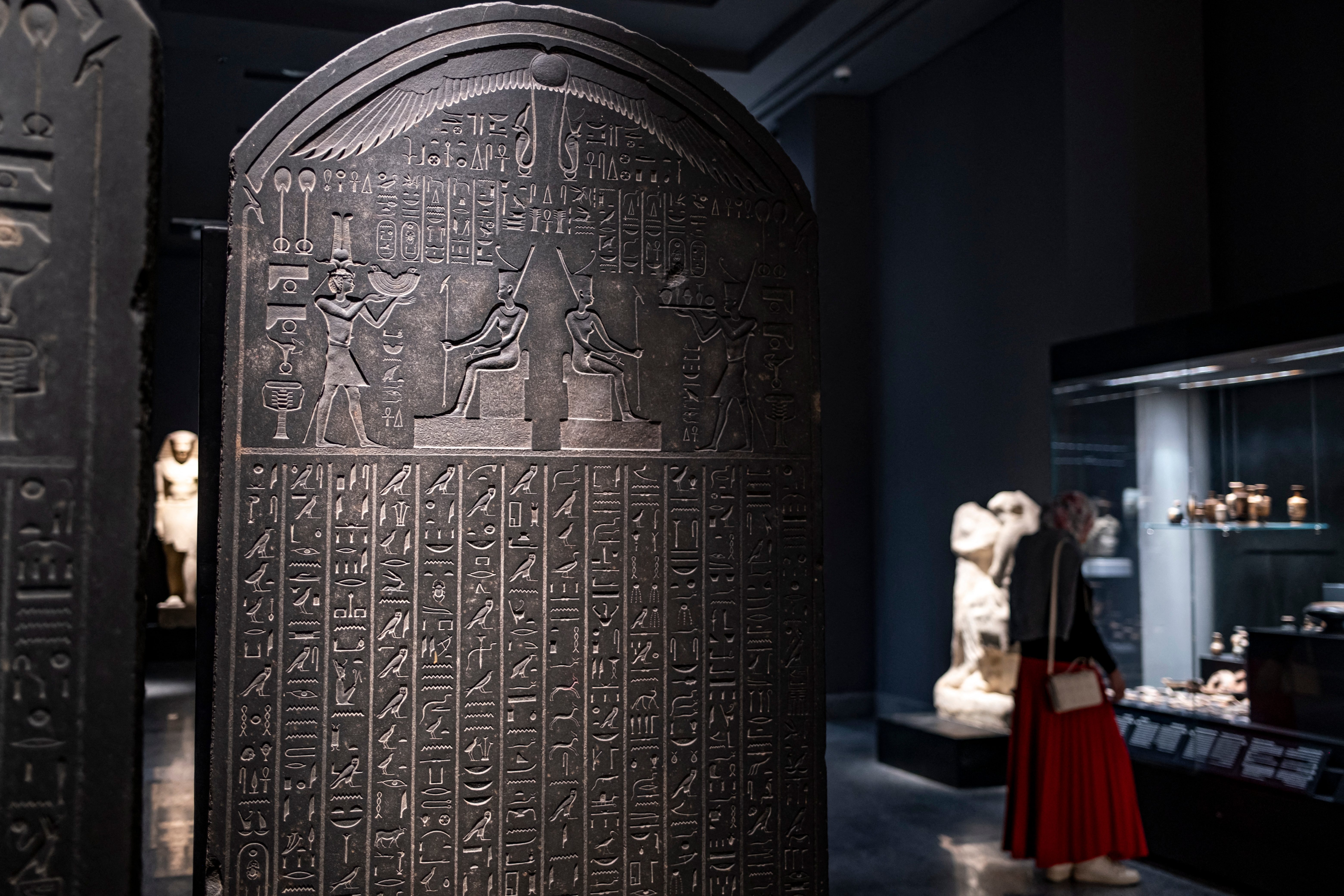 Ancient Egyptian stele with hieroglyphs displayed successful a museum; a visitant successful the inheritance observes different artifacts