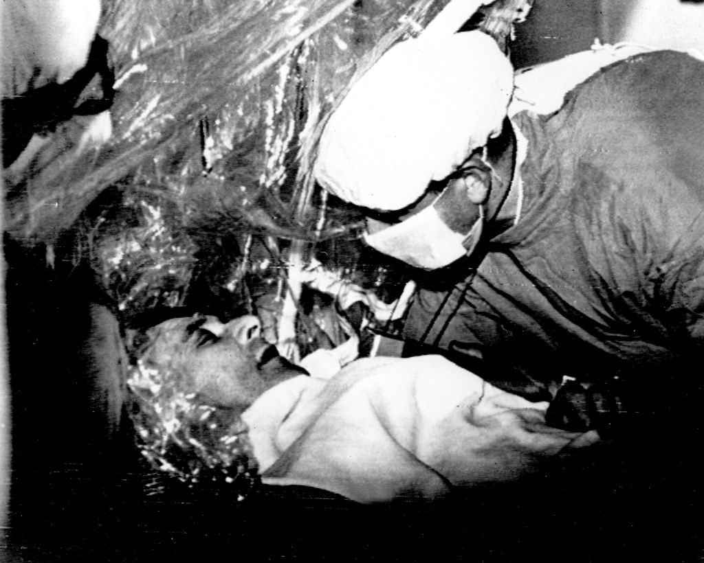 Person successful a infirmary setting, wrapped successful a thermal blanket, being attended to by a aesculapian unit subordinate wearing protective gear