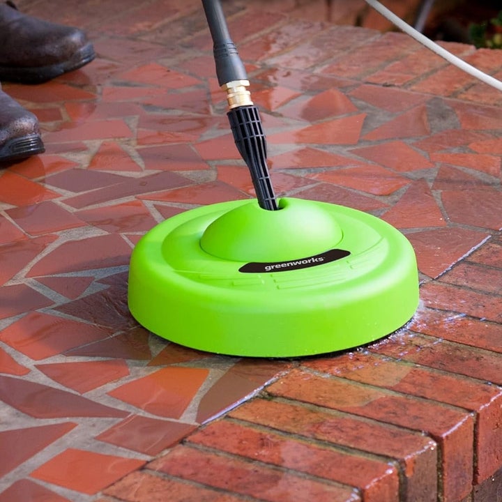 Person using the circular scrubber on a bricked patio