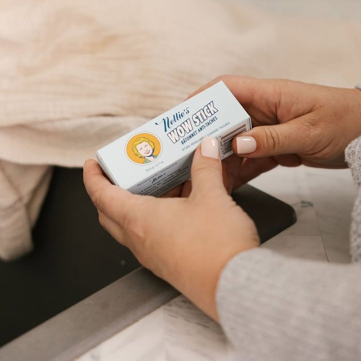Person holding a Nellie's WOW Stick, a natural stain remover, in a home setting