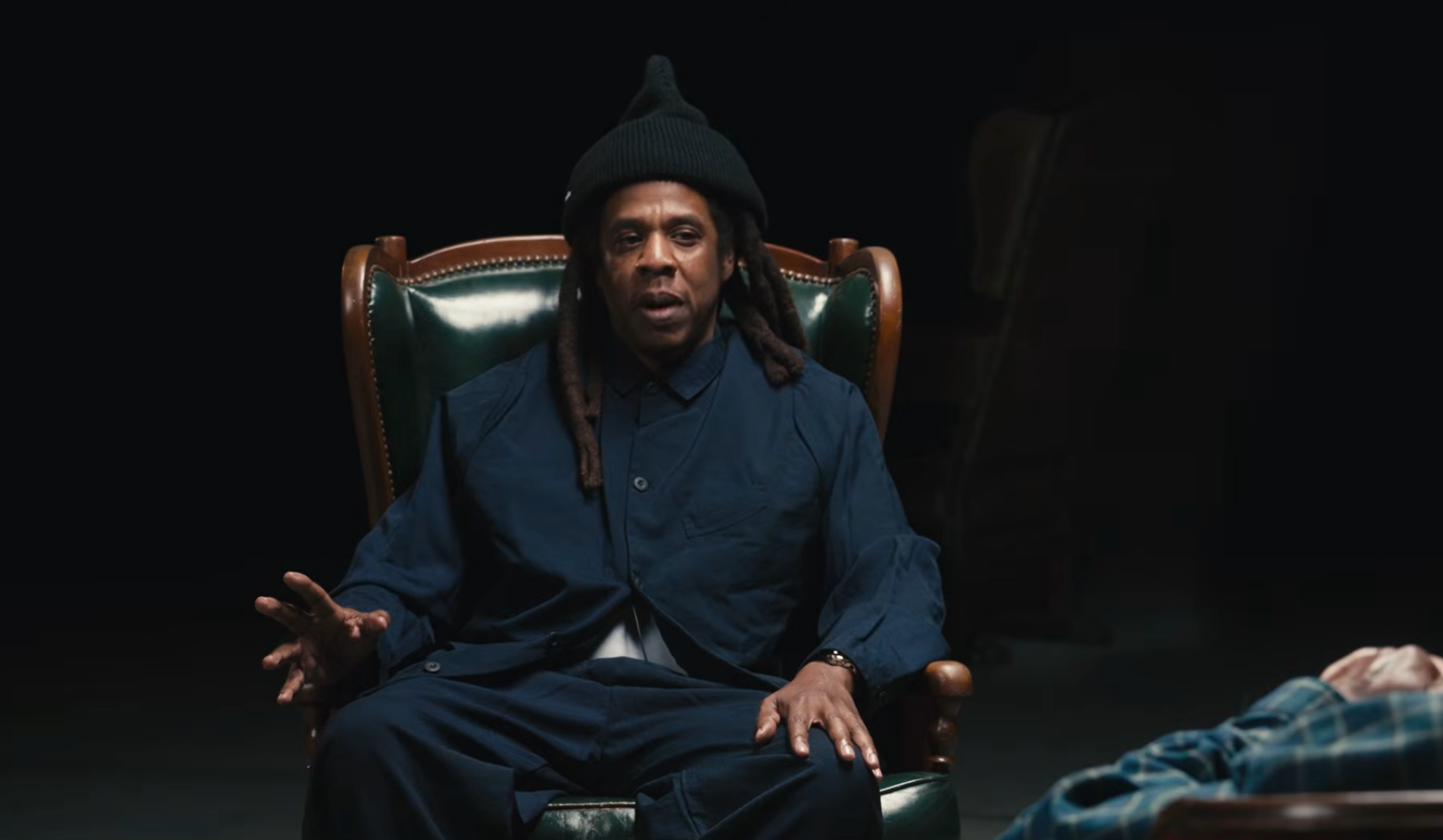 Person seated successful  a classical  chair, wearing a casual outfit and knit cap, gesturing portion    engaged successful  conversation