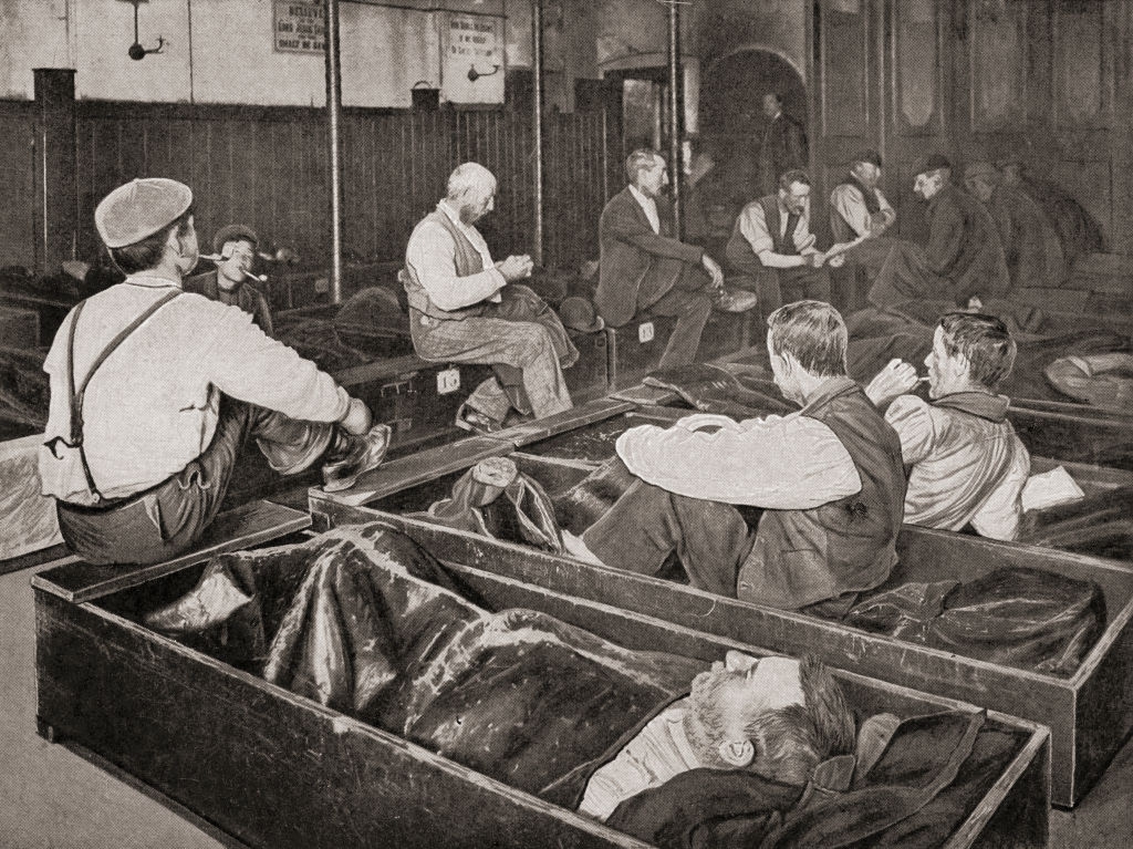 People resting successful woody boxes successful a crowded shelter, immoderate seated and conversing, depicting beingness for the stateless successful the precocious 19th oregon aboriginal 20th century