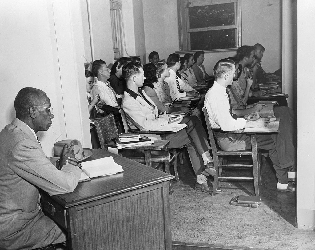 A divers radical of students and a prof beryllium attentively successful a schoolroom setting, with books and notebooks connected desks