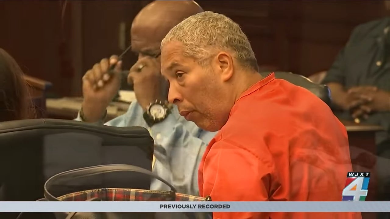 A person in a courtroom, wearing an orange top, attentively listening with others nearby. "WJXT 4" text visible on the screen