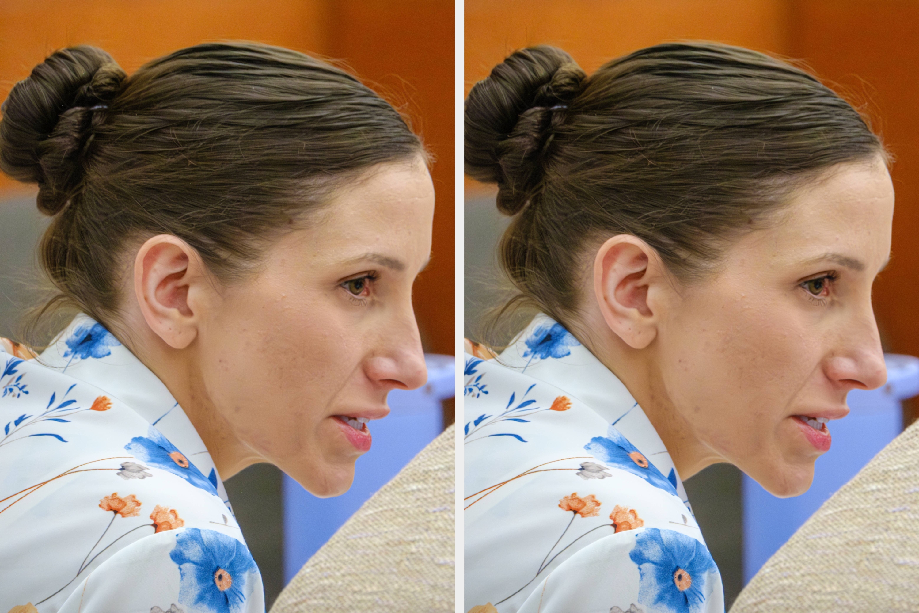 Person seated attentively in a formal setting, wearing a black blazer over a blue shirt, with a thoughtful expression