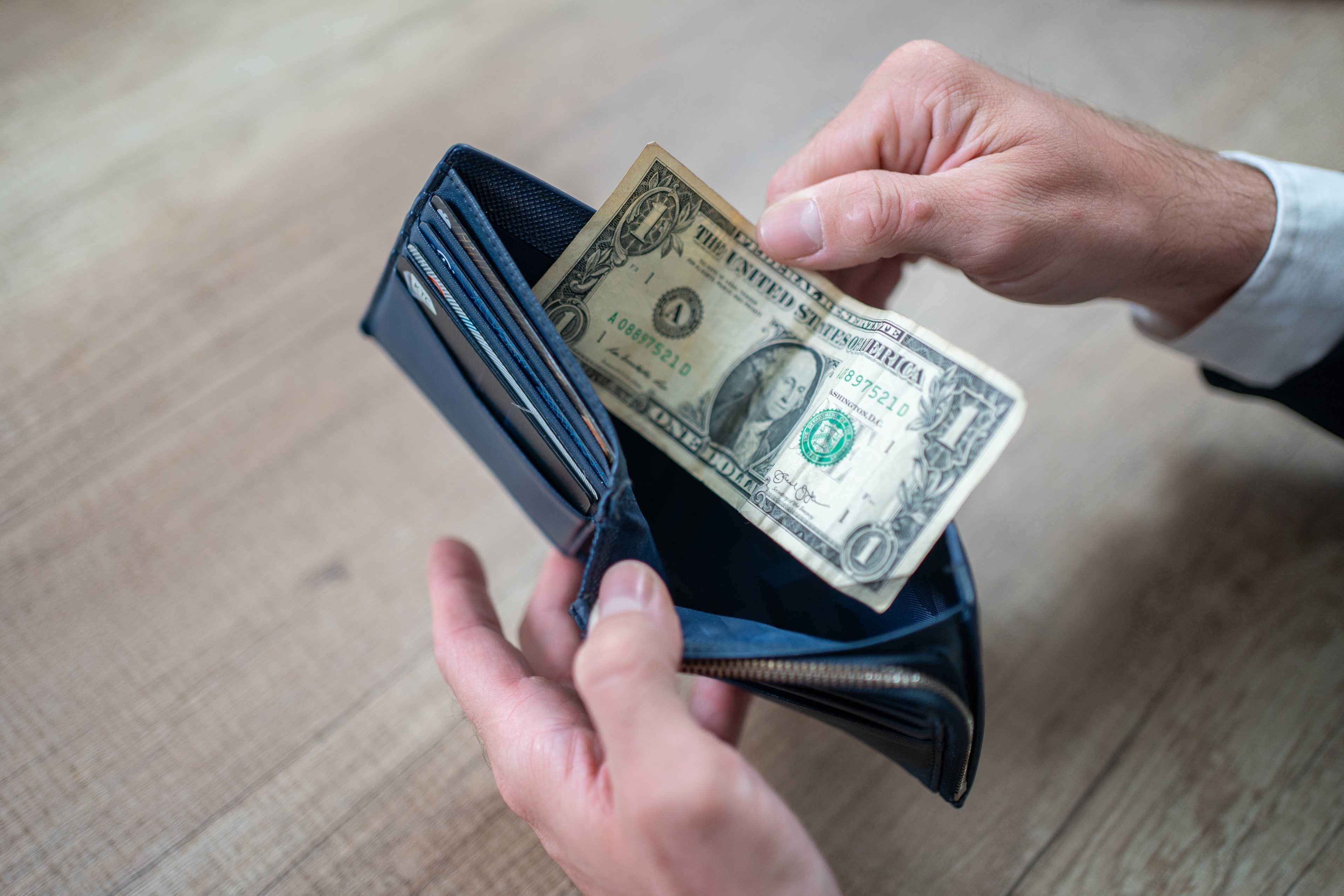 Person holding a wallet with a azygous  dollar bill, suggesting fiscal  simplicity oregon  constraint
