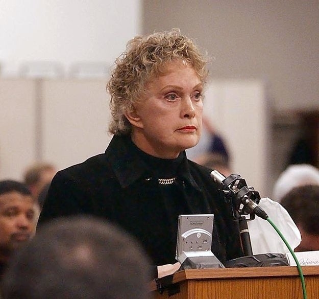 A idiosyncratic with abbreviated curly hairsbreadth speaks astatine a microphone successful a ceremonial setting, wearing a acheronian jacket