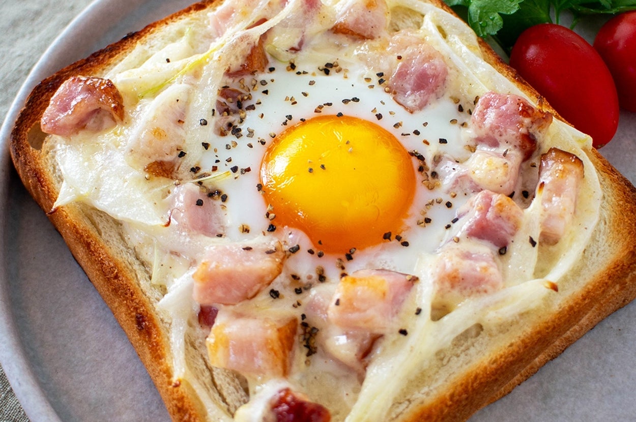 目玉焼きとハムがトッピングされたトースト、パセリとトマトが添えられています。