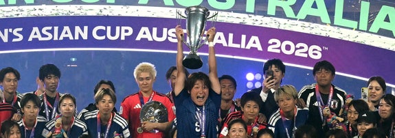 サッカー選手たちがトロフィーを掲げて喜ぶ瞬間を祝う場面。