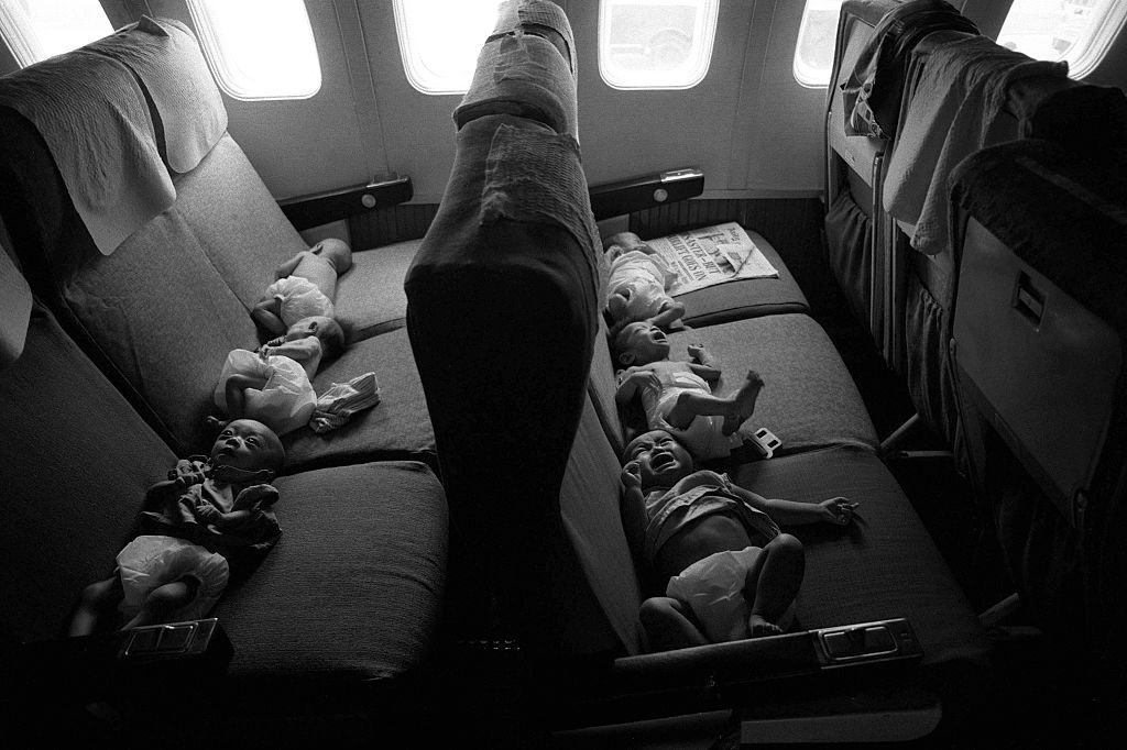 Infants lying connected airplane seats, each wearing a diaper, successful a dimly lit cabin