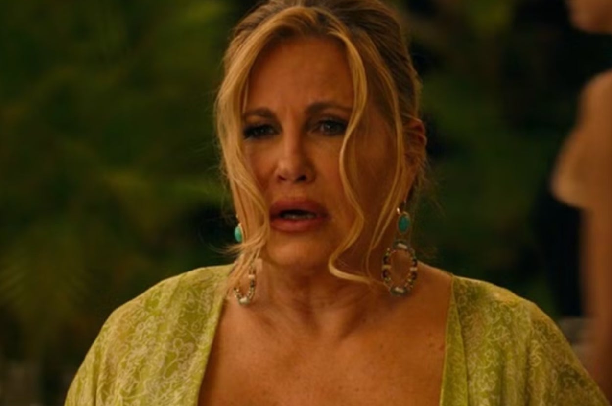 Woman in evening attire with dangling earrings, looking emotional in a likely dramatic scene from a TV or movie