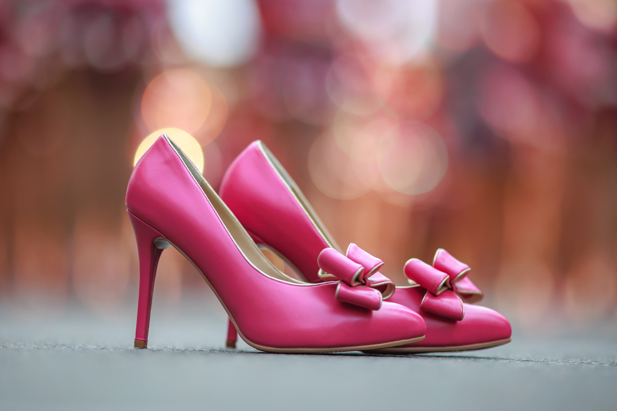 Pink high heels with bow accents on a blurred background, suitable for a glamorous date night