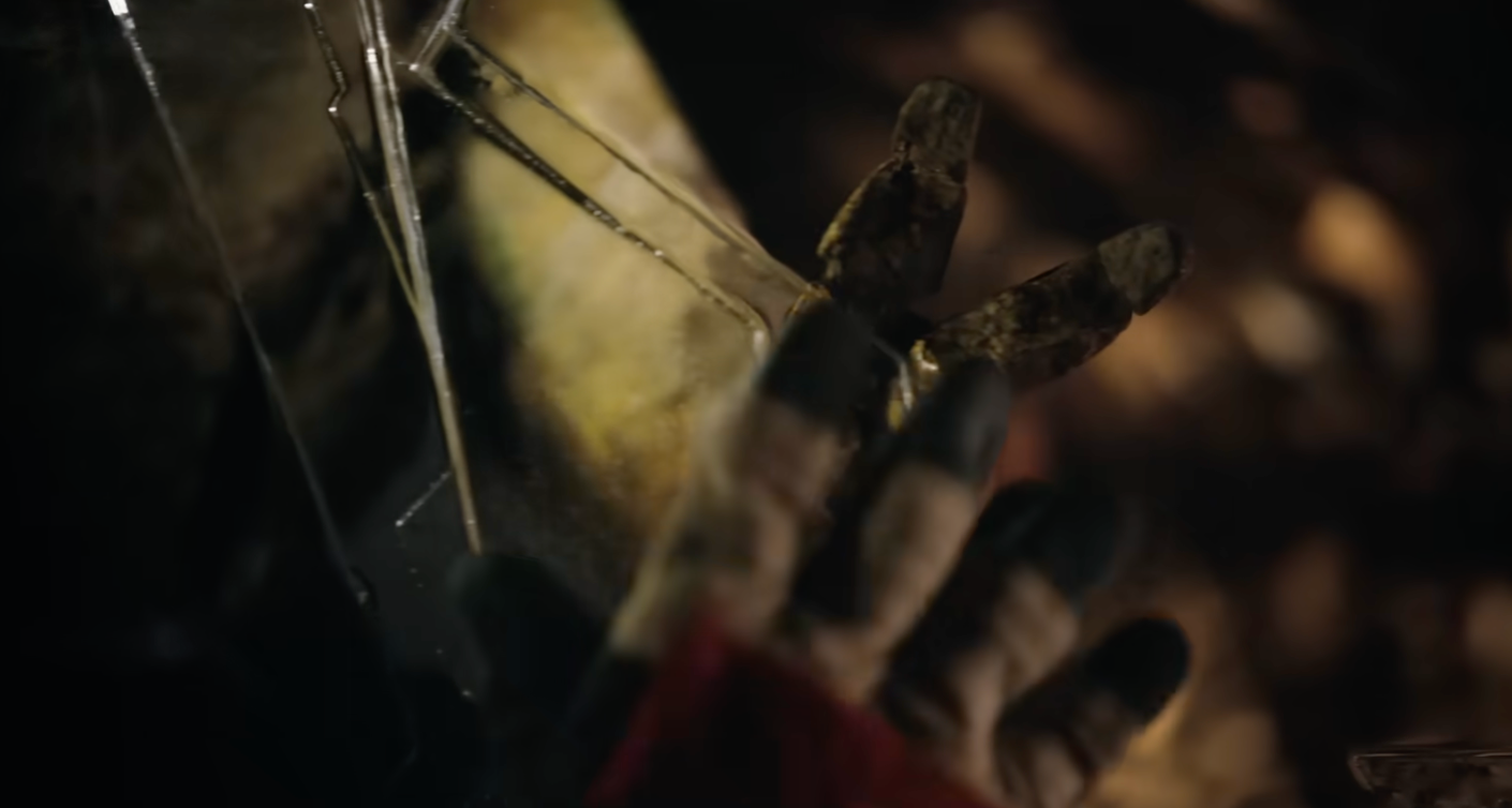 Close-up of a manus reaching toward a shattered solid aboveground with works matter, depicting a melodramatic moment