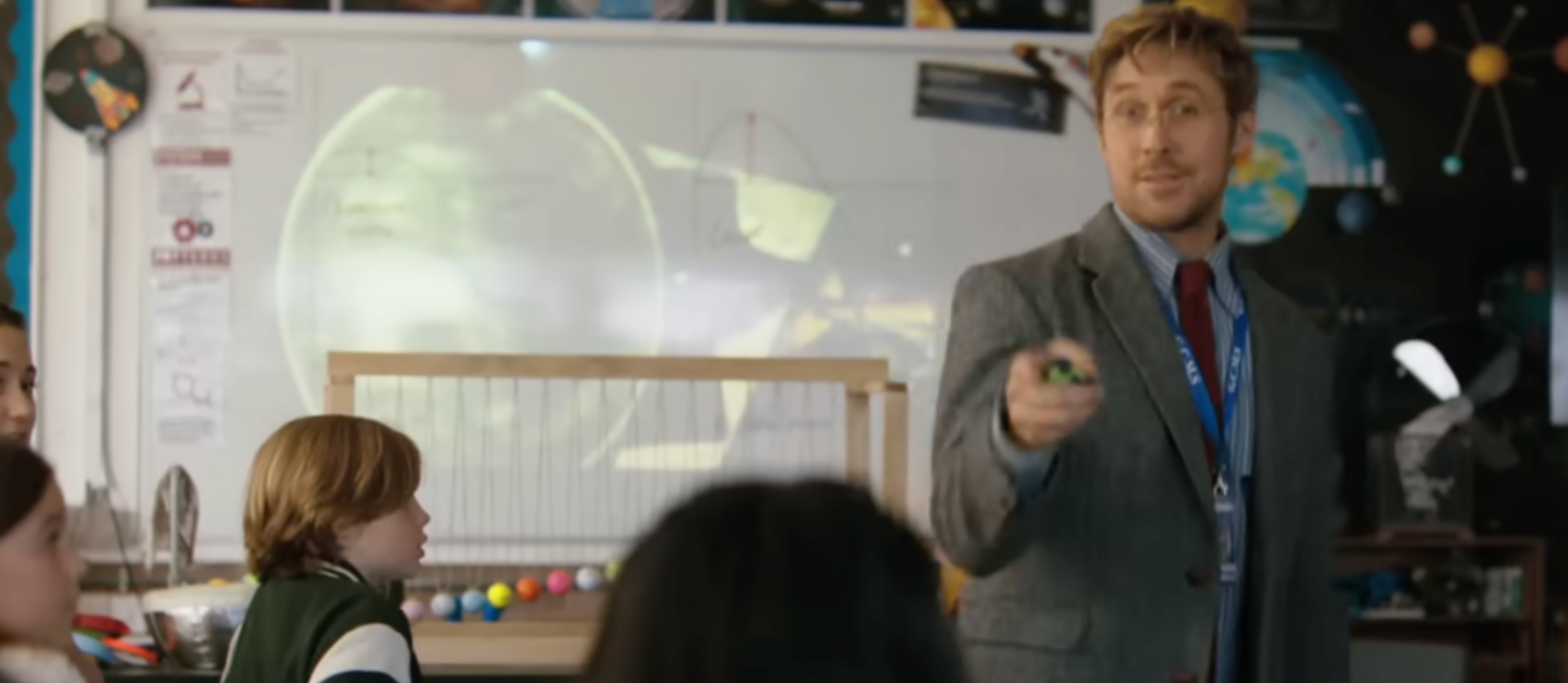 Teacher successful a necktie and blazer engaging with attentive students successful a schoolroom decorated with satellite models and space-themed visuals