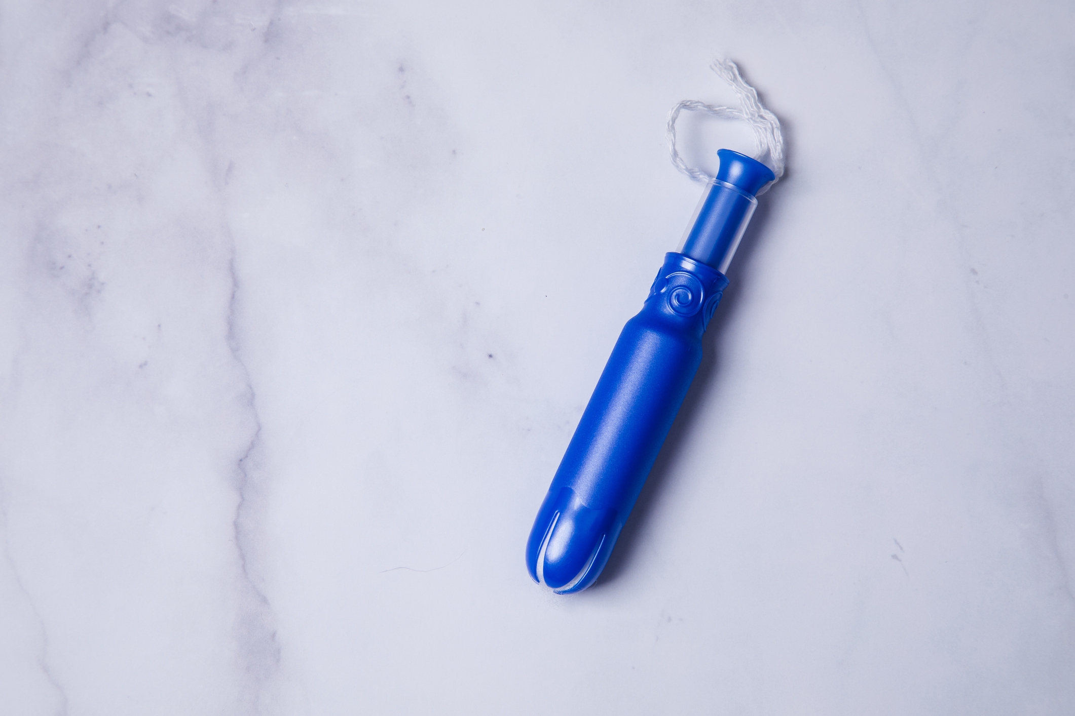Blue tampon applicator on a marble surface, shown in a Sex &amp;amp; Love article context