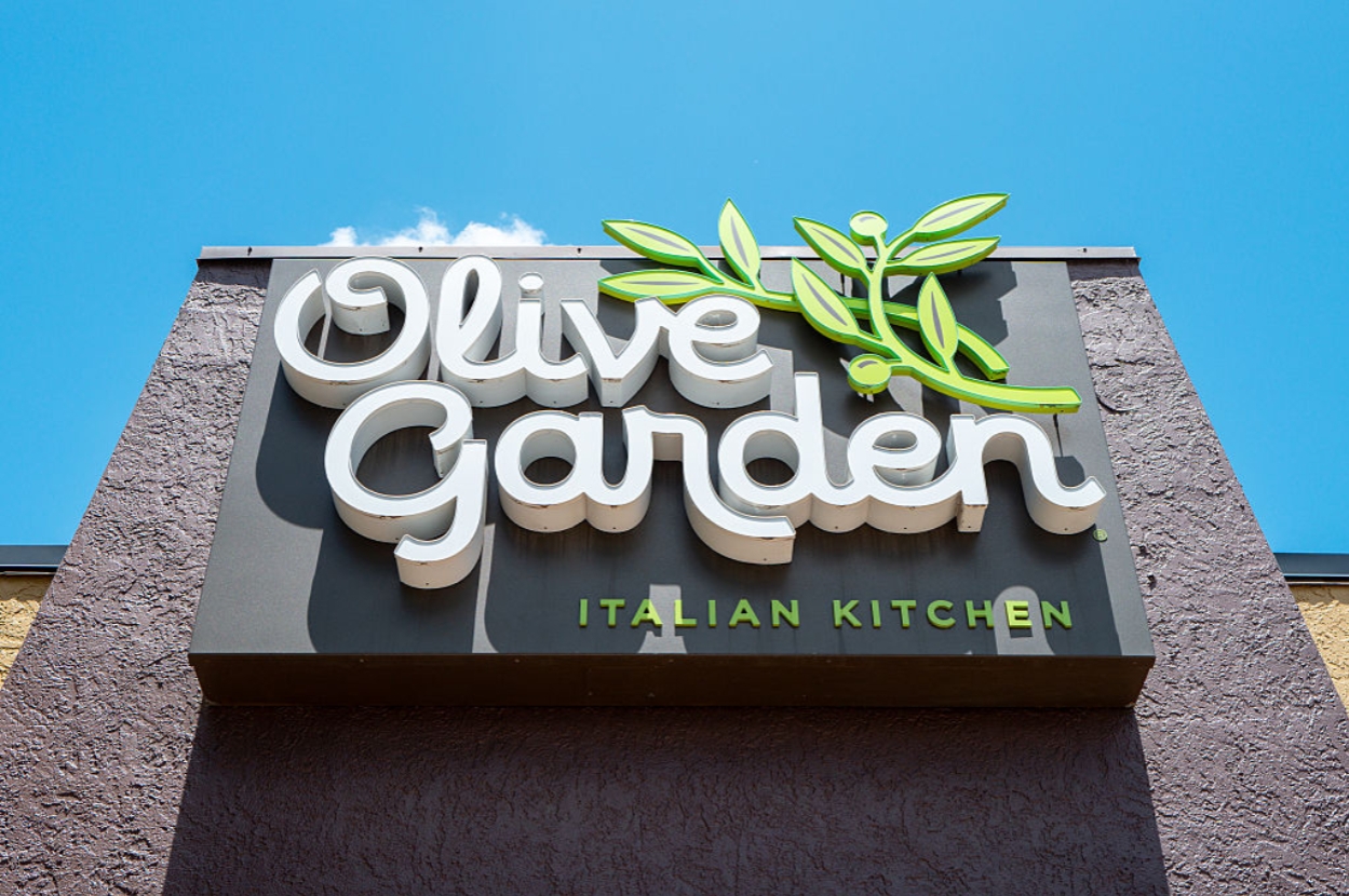 Olive Garden Italian Kitchen sign on a building exterior, featuring a stylized olive branch logo