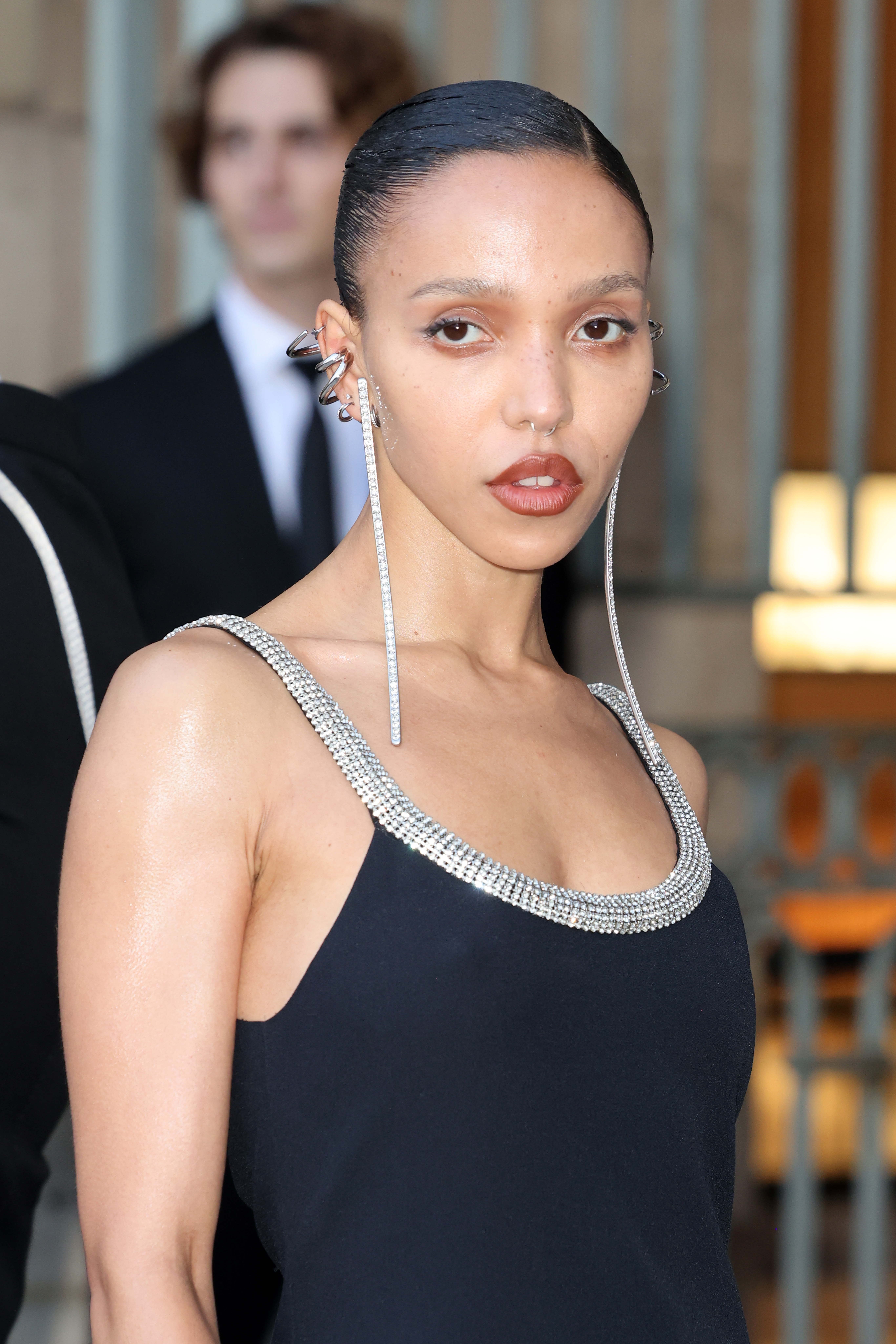 Person successful  a sleek outfit with a jeweled neckline connected  a reddish  carpet. Hair styled back, with agelong  earrings