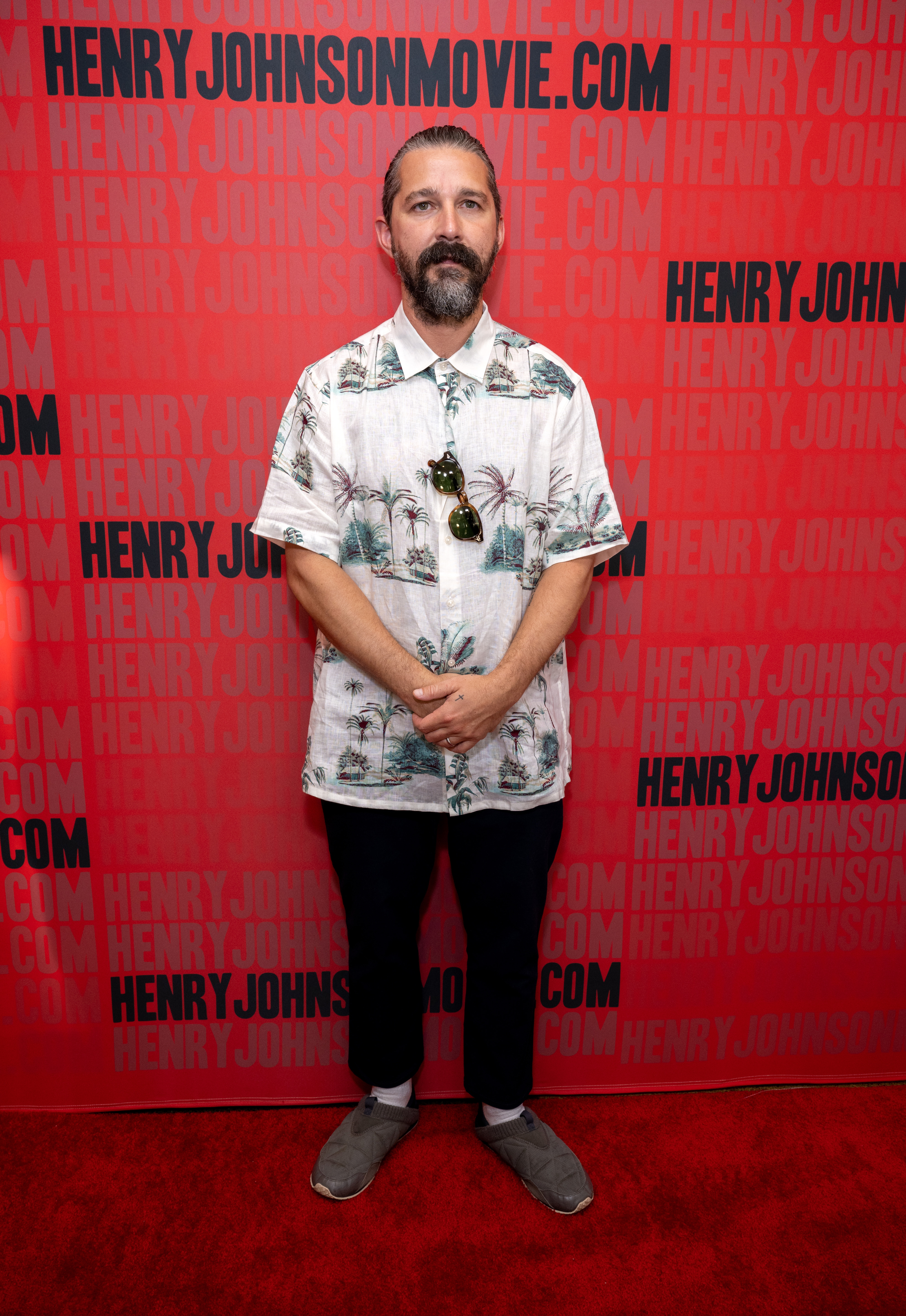 Individual connected  the reddish  carpet wearing a tropical-patterned shirt, achromatic  pants, and grey  shoes astatine  a movie   event