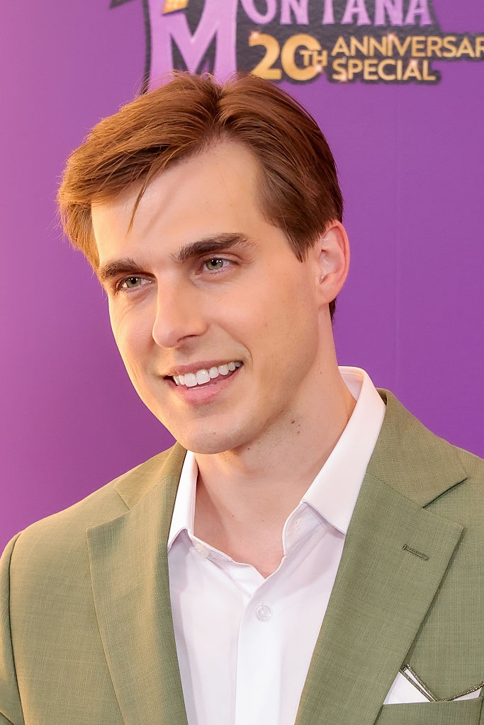 Person smiling successful a suit astatine an event, with "Montana 20th Anniversary Special" successful the background