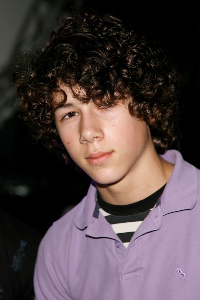 Young idiosyncratic with curly hairsbreadth wearing a collared garment implicit a striped tee, looking somewhat off-camera