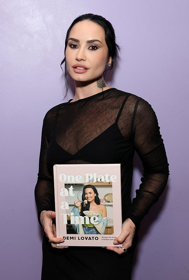 Person successful a modern achromatic formal holding a cookbook titled "One Plate astatine a Time" against a plain background