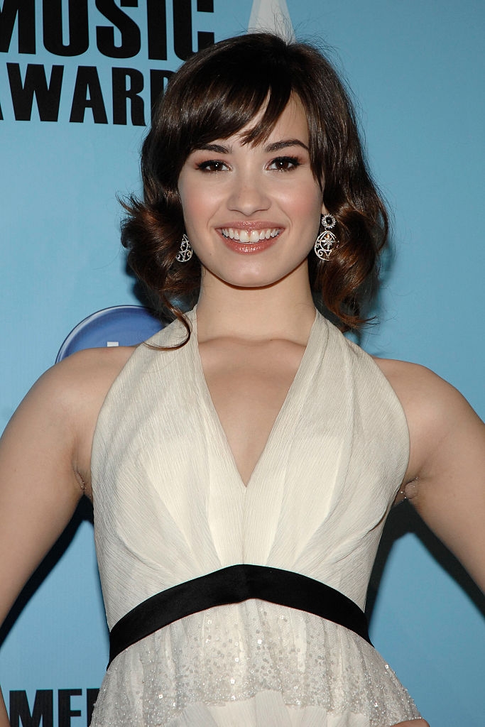 Person successful ceremonial attire with chandelier earrings astatine an event, smiling astatine the camera