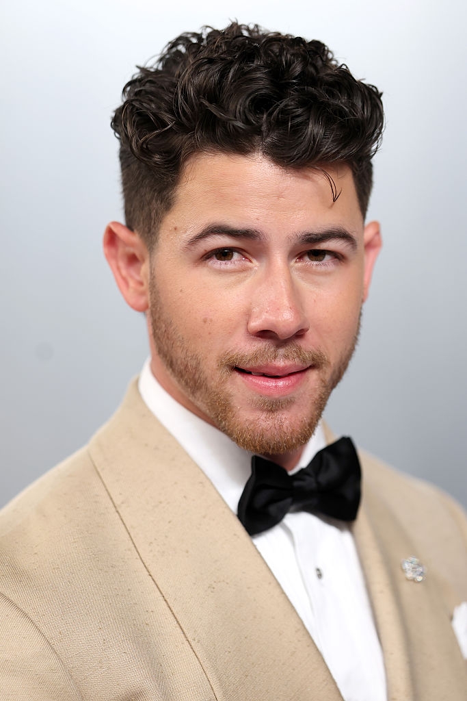 Person successful a beige suit with a achromatic garment and achromatic bow necktie smiles astatine the camera