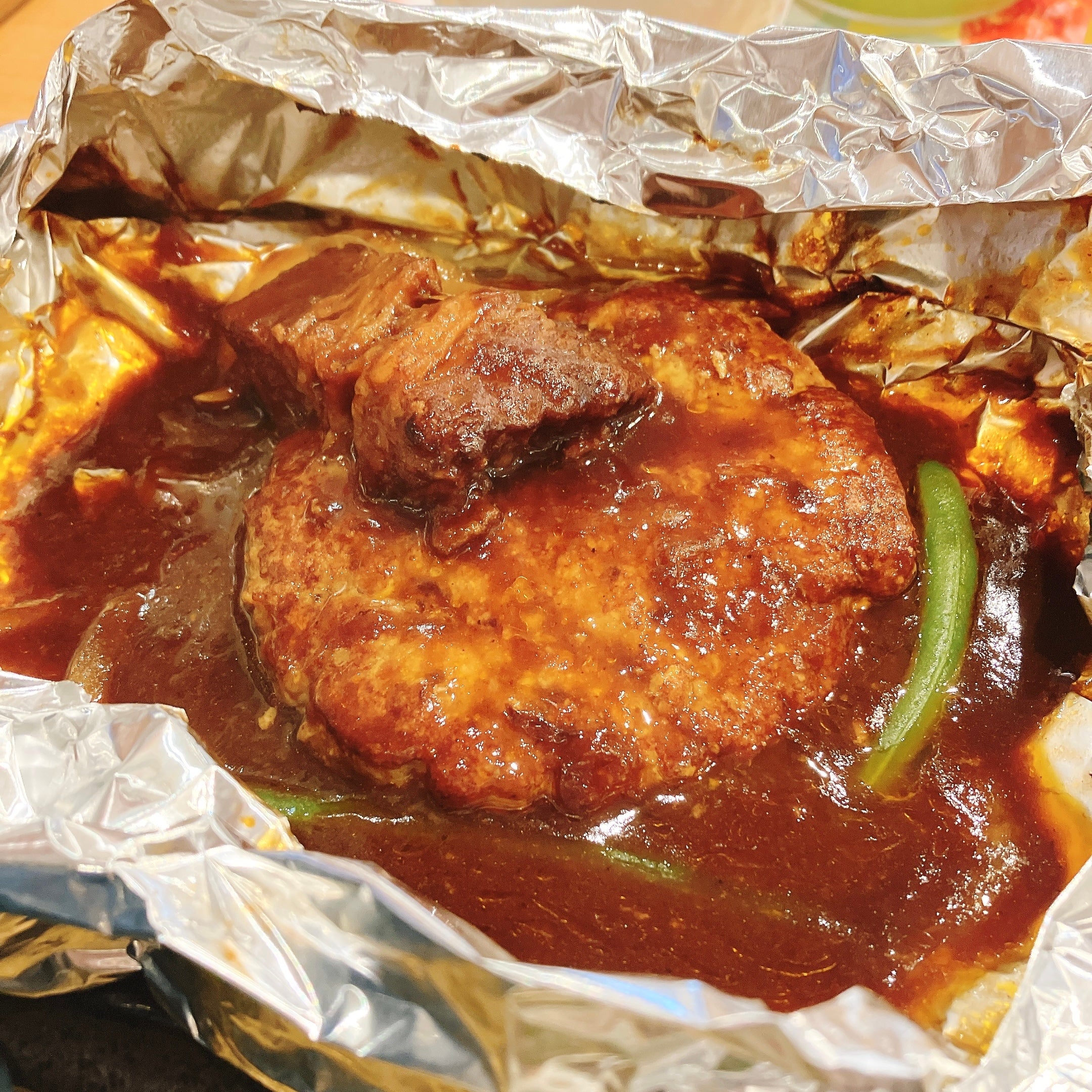 COCO'S（ココス）のモーニング限定メニュー「包み焼きハンバーグの朝定食」ホイルに包まれたハンバーグステーキがデミグラスソースの中で焼かれている様子。