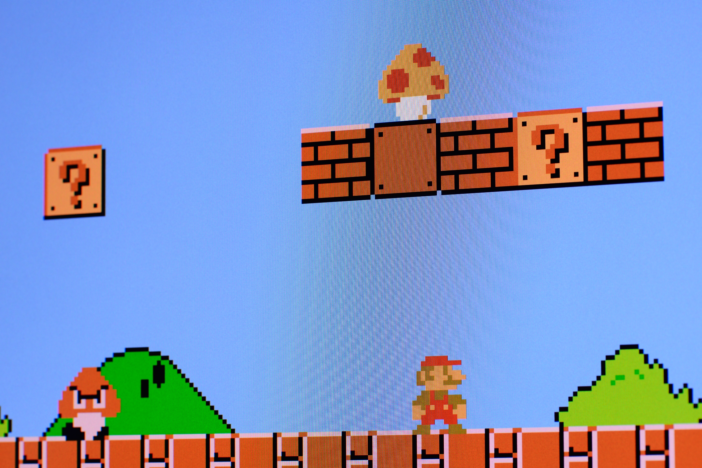 Screenshot of a classical video crippled level featuring a quality moving beneath ceramic blocks, 1 marked with a question mark, and a Goomba enemy
